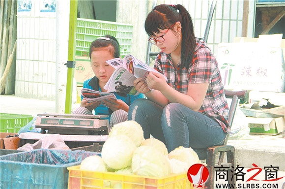 商州區楊斜鎮集市上,南思佳和妹妹在幫父母賣菜,閑暇之余,她們會拿起課外讀物翻一翻。在這個假期里,她們呆的最多的地方就是這個菜攤。
